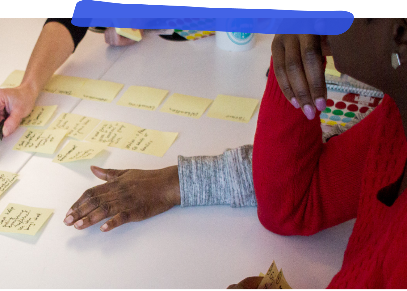 People huddled around a desk full of sticky notes in the middle of participating in a design sprint